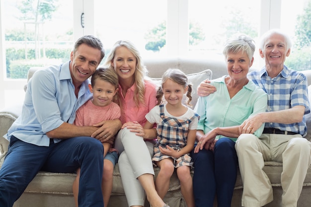 Famiglia della multi generazione che si siede sul sofà in salone