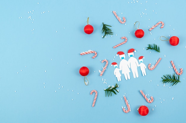 Famiglia di carta tagliata con maschere a Natale. Nuova normalità dalla distanza sociale del coronavirus a Natale. Copia spazio.