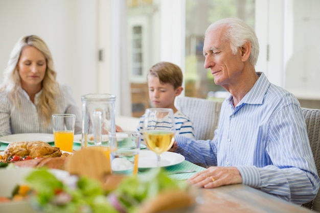 Famiglia di diverse generazioni che prega prima di consumare il pasto