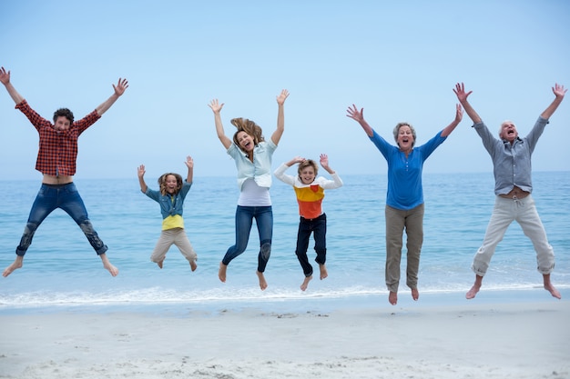 Famiglia di diverse generazioni che salta in riva al mare