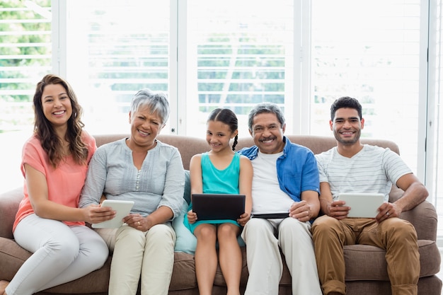 Famiglia di diverse generazioni che utilizza compressa digitale nel salone a casa