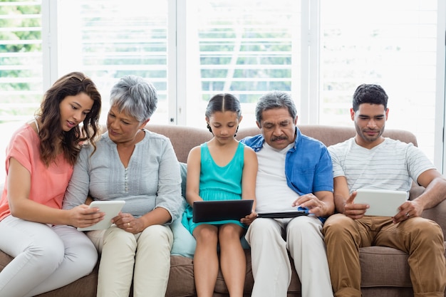 Famiglia di diverse generazioni che utilizza la compressa digitale nel salone