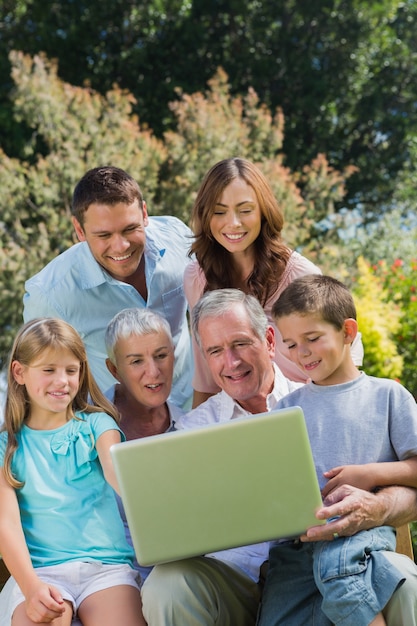 Famiglia di multi generazione con un computer portatile che si siede nel parco