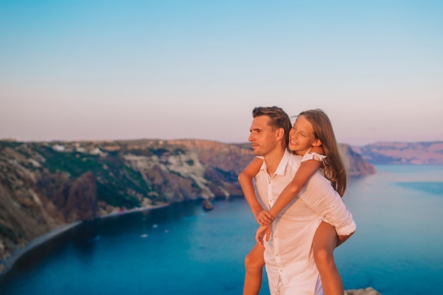 Famiglia di papà e la sua piccola figlia sul bordo della scogliera al tramonto