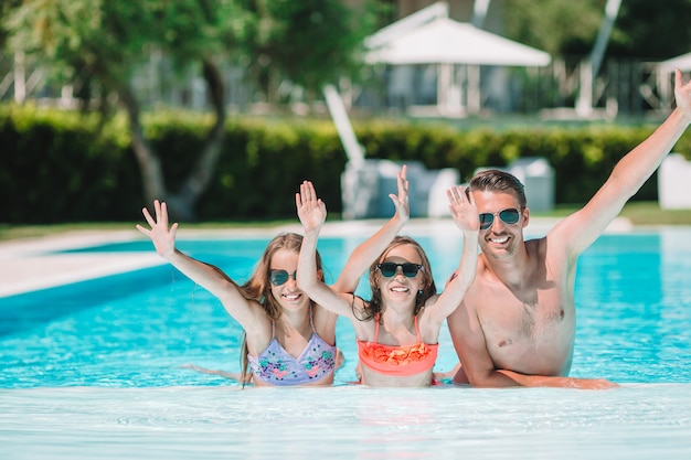 Famiglia di quattro felice nella piscina all'aperto