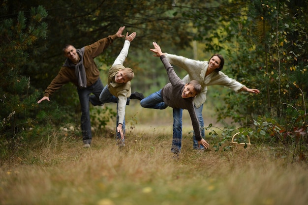 Famiglia di quattro persone che camminano nella foresta d'autunno