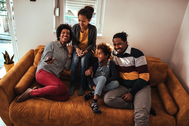 Famiglia di quattro persone che guardano la tv dal divano di casa