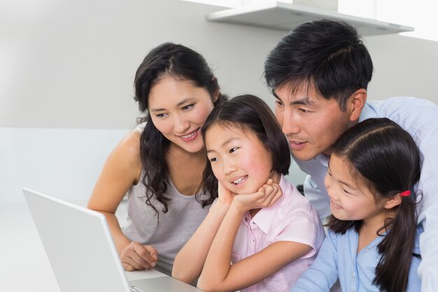 Famiglia di quattro persone con laptop in cucina