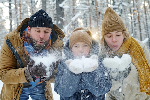 Famiglia di tre persone che giocano con la neve