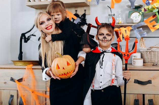 Famiglia divertente in cucina in piedi in costume e guardando la telecamera Halloween
