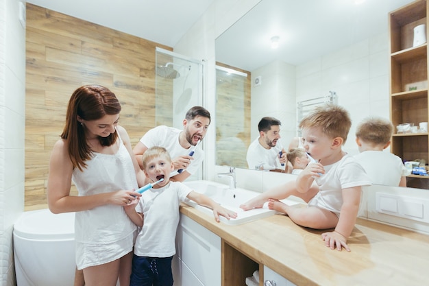 famiglia, due adulti e due bambini piccoli si lavano i denti insieme in bagno