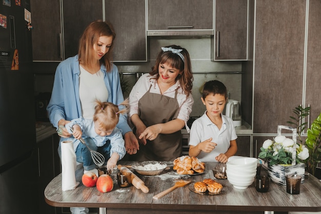 Famiglia: due donne e bambini stanno preparando una torta di compleanno in cucina.