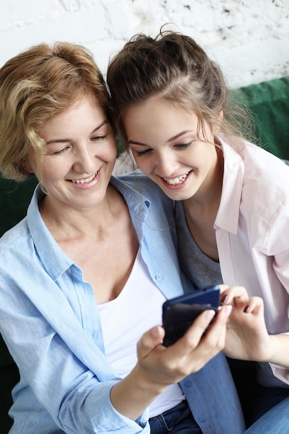 Famiglia e tecnologia Donna anziana e sua figlia adulta che utilizzano lo smartphone a casa