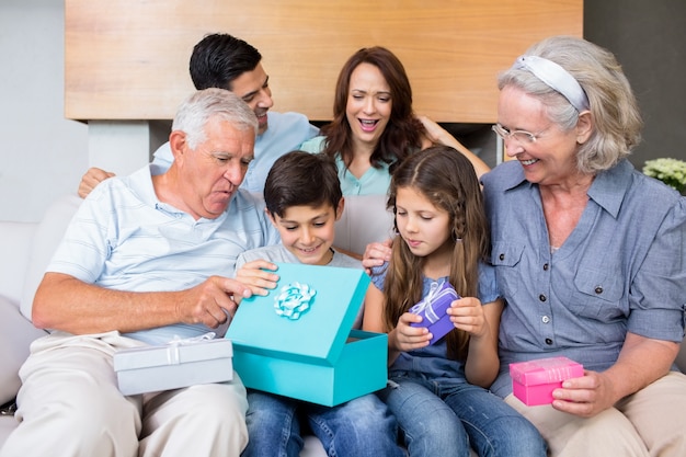 Famiglia estesa che si siede sul sofà con i contenitori di regalo in salone