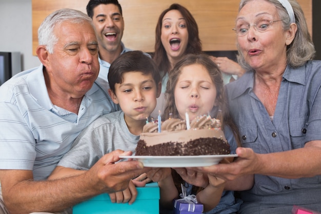 Famiglia estesa che soffia candele sul dolce nel salotto