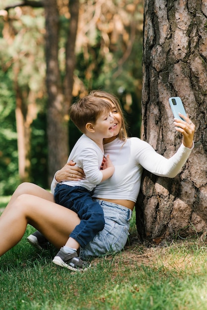 Famiglia europea che si diverte una madre e suo figlio che si fanno un selfie con un cellulare nel parco insieme il concetto di persone di amore e felicità