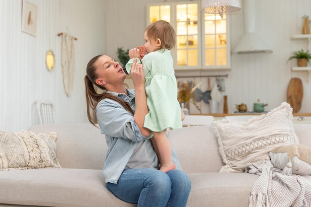 Famiglia felice a casa madre che solleva in aria piccola figlia bambino mamma e bambina che giocano h