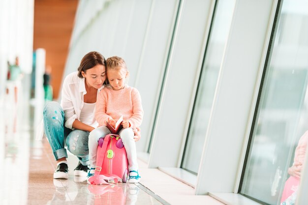 Famiglia felice all&#39;aeroporto che si siede sulla valigia con la carta d&#39;imbarco che aspetta imbarco