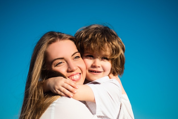 Famiglia felice all'aperto. Maternità. Figlio abbraccia la madre. Giovane famiglia sorridente con bambino. I bambini amano e abbracciano la mamma. Faccia sorridente. Festa della mamma.