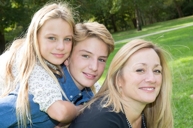 Famiglia felice all'aperto sull'erba nel parco volti sorridenti