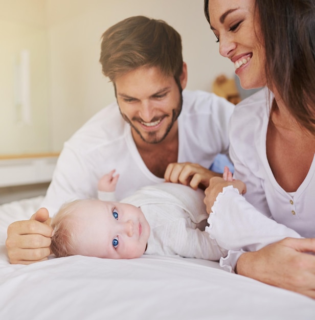 Famiglia felice bambino e genitori a letto per la cura dell'amore e del tempo di qualità insieme in casa Mamma papà e bambino appena nato si rilassano nella camera da letto di casa per lo sviluppo dell'infanzia supporto premuroso e felicità