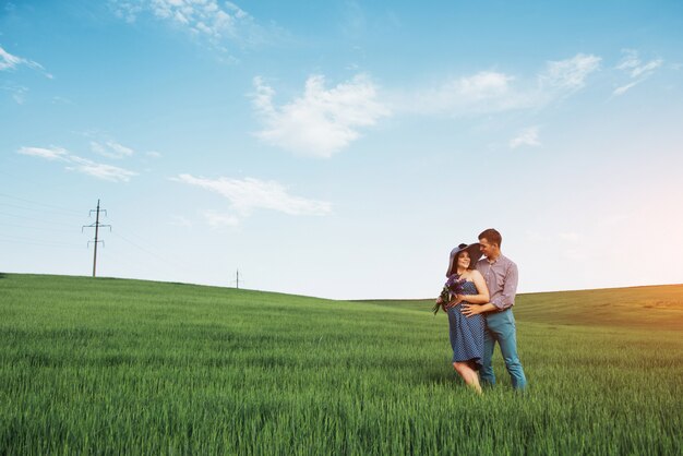 Famiglia felice che abbraccia in un campo di grano verde