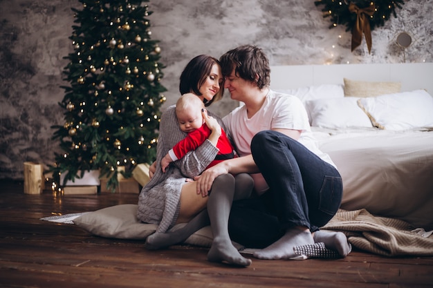 Famiglia felice che abbraccia sopra l'albero di Natale a casa