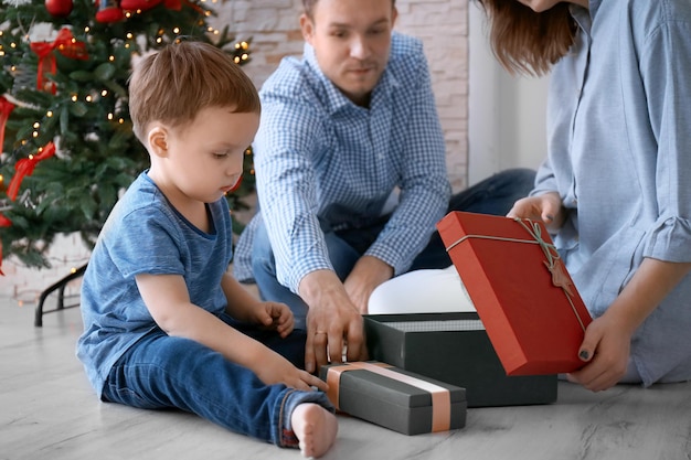 Famiglia felice che apre scatole regalo vicino all'albero di Natale a casa