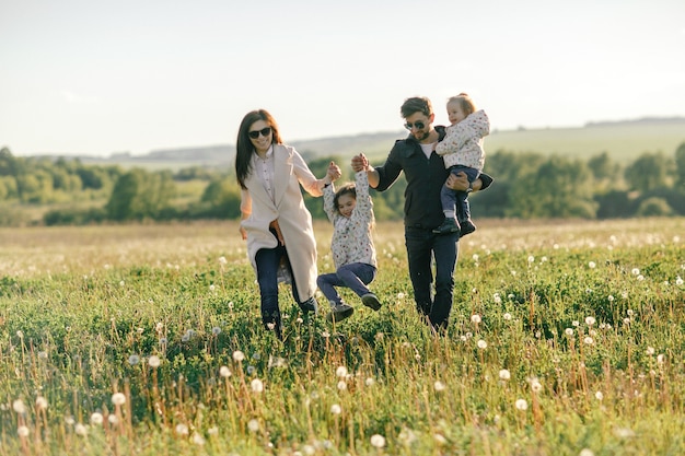 Famiglia felice che attraversa il campo. Papà, mamma e due figlie.