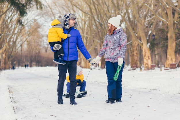 Famiglia felice che cammina insieme a winter park, due adulti uomo e donna e due bambini