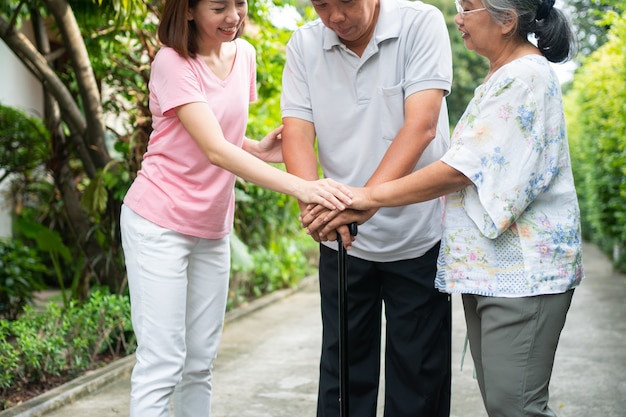 Famiglia felice che cammina insieme nel giardino. Anziani anziani che usano un bastone da passeggio per aiutare a camminare in equilibrio. Concetto di amore e cura della famiglia e assicurazione sanitaria per la famiglia