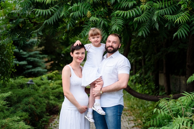 Famiglia felice che cammina nel parco. Gravidanza.