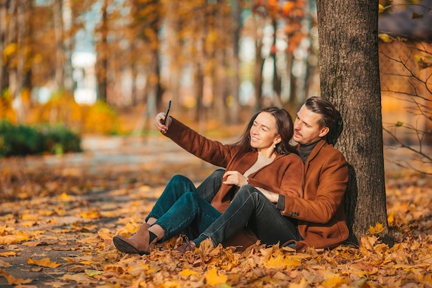 Famiglia felice che cammina nella sosta di autunno sulla giornata di sole autunnale