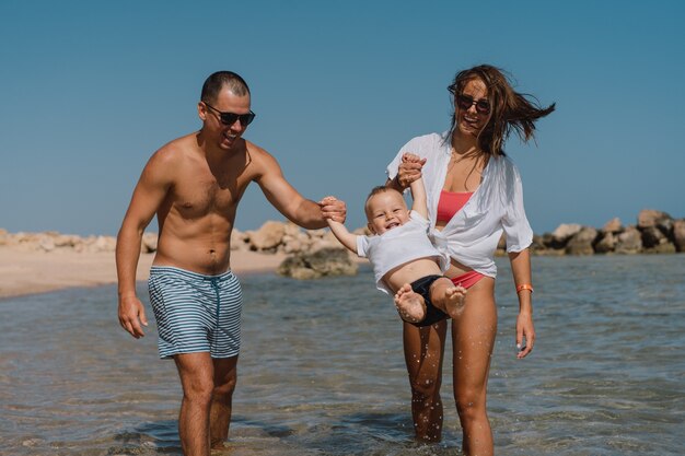 Famiglia felice che cammina su una spiaggia tenendosi per mano