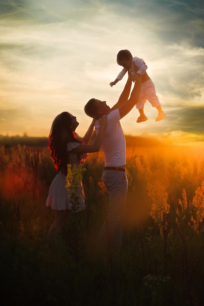 Famiglia felice che cammina sul campo in natura al tramonto