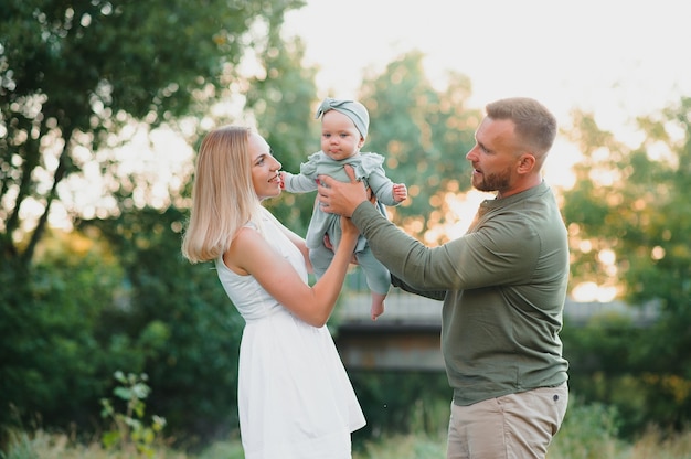 Famiglia felice che cammina sul campo in natura al tramonto