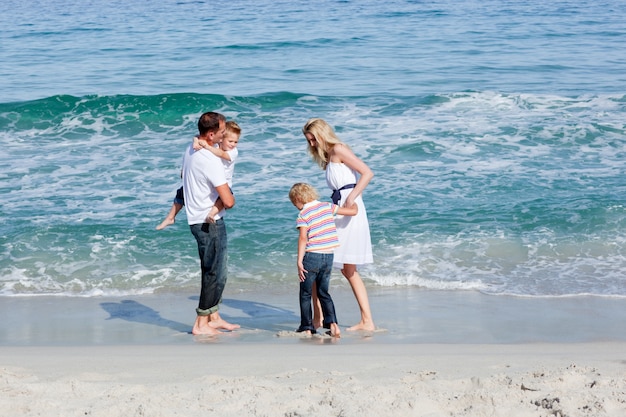 Famiglia felice che cammina sulla sabbia