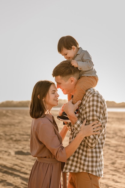 Famiglia felice che cammina sulla spiaggia sabbiosa