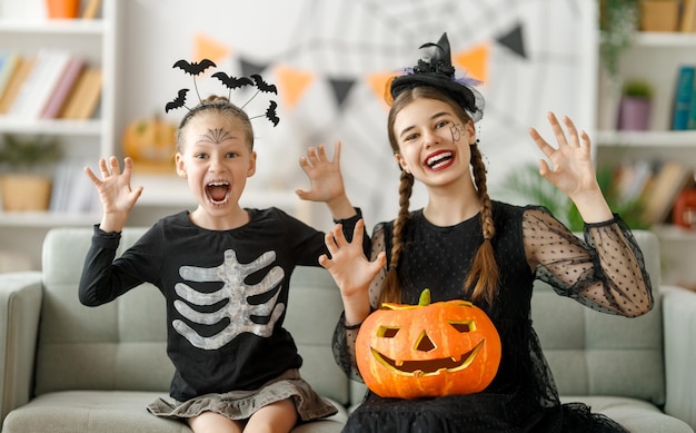 Famiglia felice che celebra Halloween Bambini carini in costumi di carnevale con zucche intagliate a casa