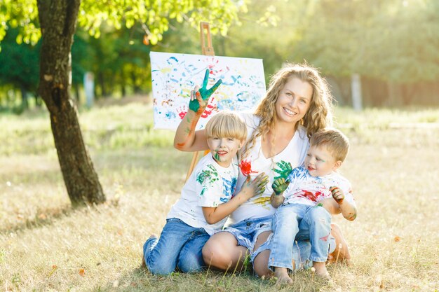 Famiglia felice che disegna all'aperto. Giovane madre si diverte con i suoi bambini piccoli