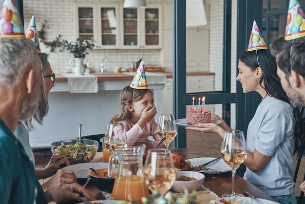 Famiglia felice che festeggia il compleanno della bambina mentre è seduta al tavolo da pranzo a casa