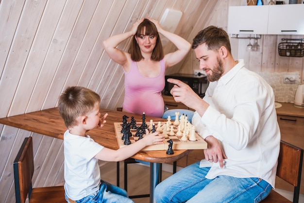 Famiglia felice che gioca a scacchi in cucina