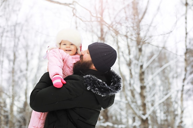 Famiglia felice che gioca e ride in inverno all'aperto nella neve. Giornata invernale del parco cittadino.