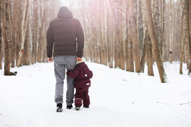 Famiglia felice che gioca e ride in inverno all'aperto nella neve. Giornata invernale del parco cittadino.