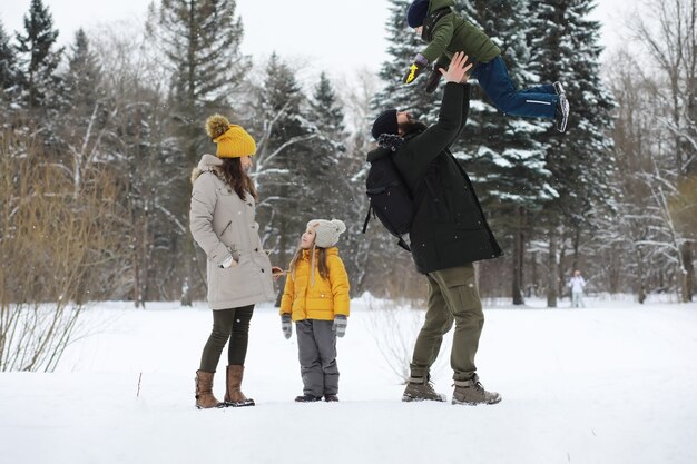 Famiglia felice che gioca e ride in inverno all'aperto nella neve. Giornata invernale del parco cittadino.