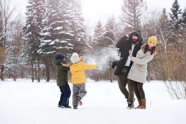 Famiglia felice che gioca e ride in inverno all'aperto nella neve. Giornata invernale del parco cittadino.