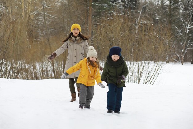 Famiglia felice che gioca e ride in inverno all'aperto nella neve. Giornata invernale del parco cittadino.