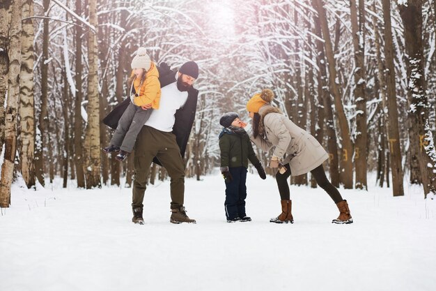 Famiglia felice che gioca e ride in inverno all'aperto nella neve. Giornata invernale del parco cittadino.