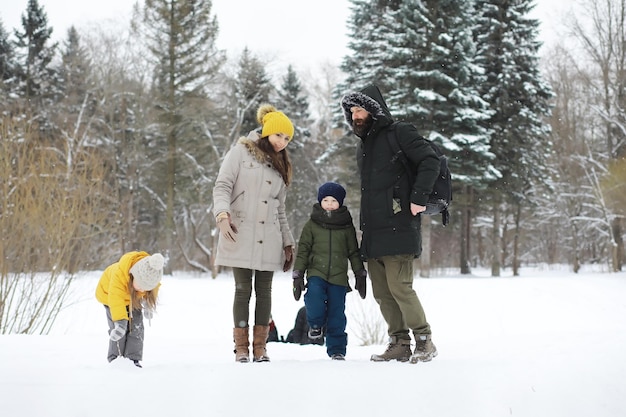 Famiglia felice che gioca e ride in inverno all'aperto nella neve. Giornata invernale del parco cittadino.