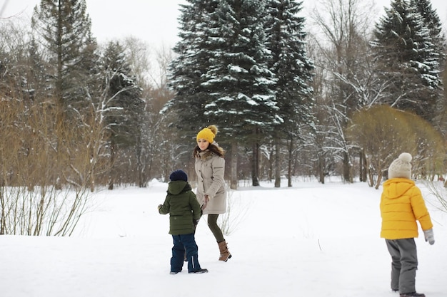 Famiglia felice che gioca e ride in inverno all'aperto nella neve. Giornata invernale del parco cittadino.